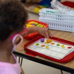 Child playing educational fruit matching game in classroom.