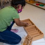 Child engaging with Montessori counting rods in classroom.