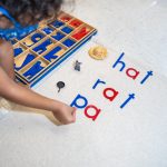 Child arranging colorful letters on classroom floor mat