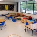 Preschool classroom with blue chairs and educational toys.