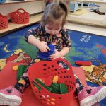 Child playing with colorful building blocks in classroom.