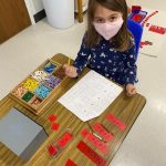 Child wearing mask doing math activity in classroom.