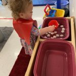 Child playing with water and ice in sensory bin