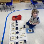 Child playing with geometric shapes in classroom setting.